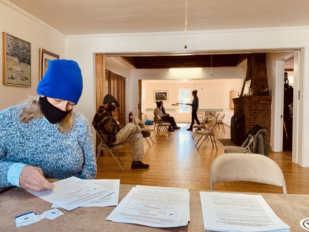 A volunteer sits in a building and goes through health paperwork