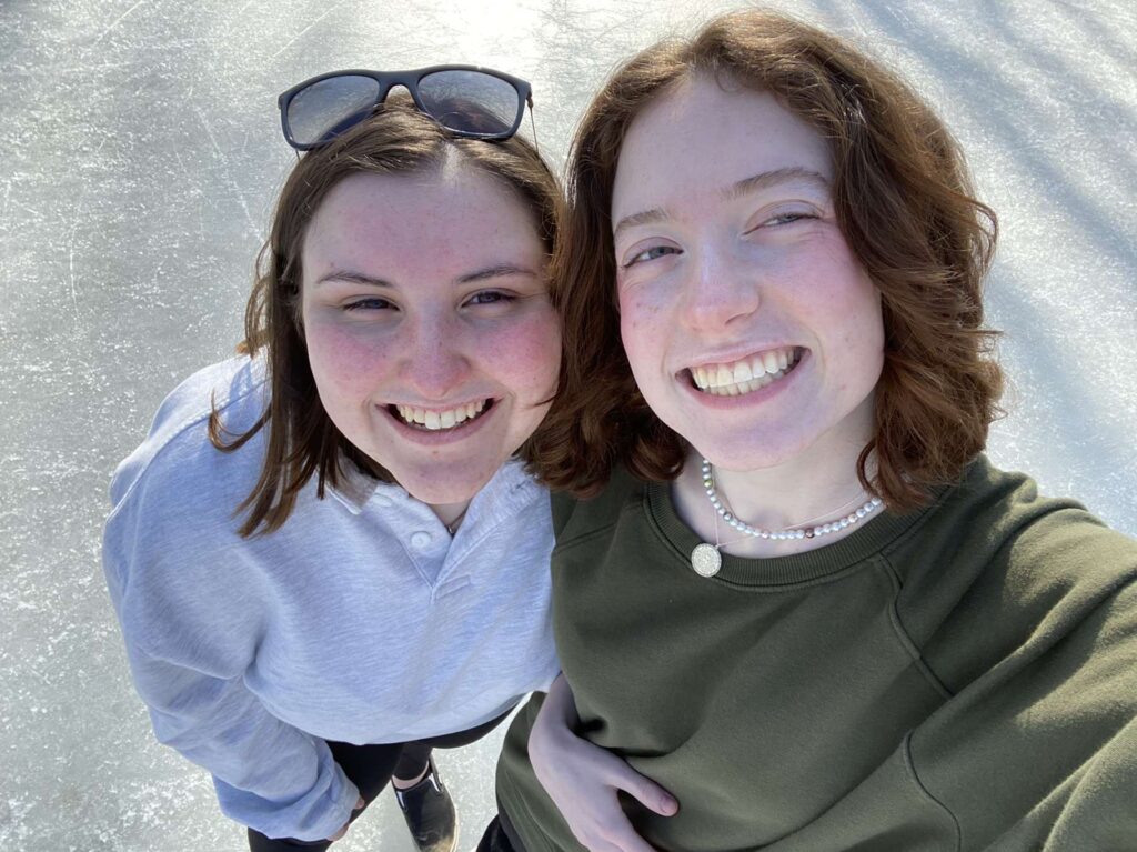 Color photo of two students smiling and looking up at the camera.