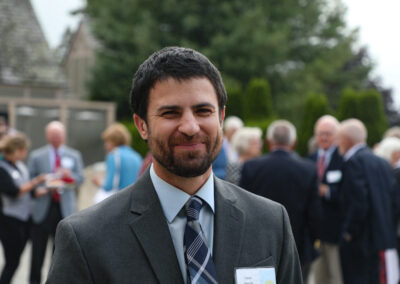 Color photo of EdGE Program Director Isaac Marnik smiles while standing on the veranda. He has a dark brown hair and beard.