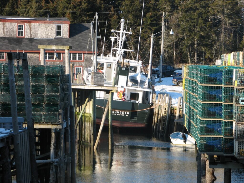 A color photo of the Sunbeam at low-tide at Matinicus harbor, listing towards the dock
