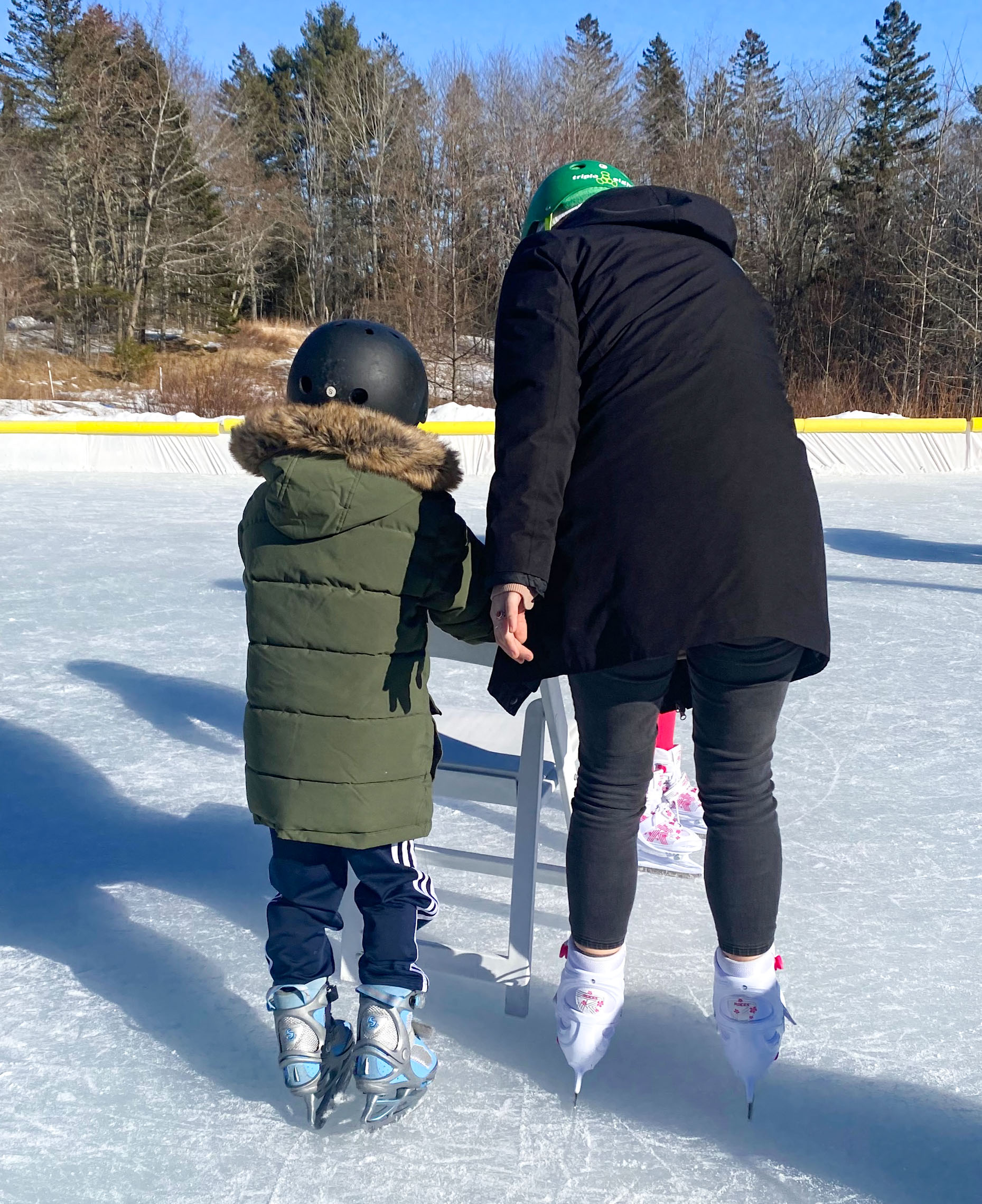 A color photo of a person helping a child learning to skate