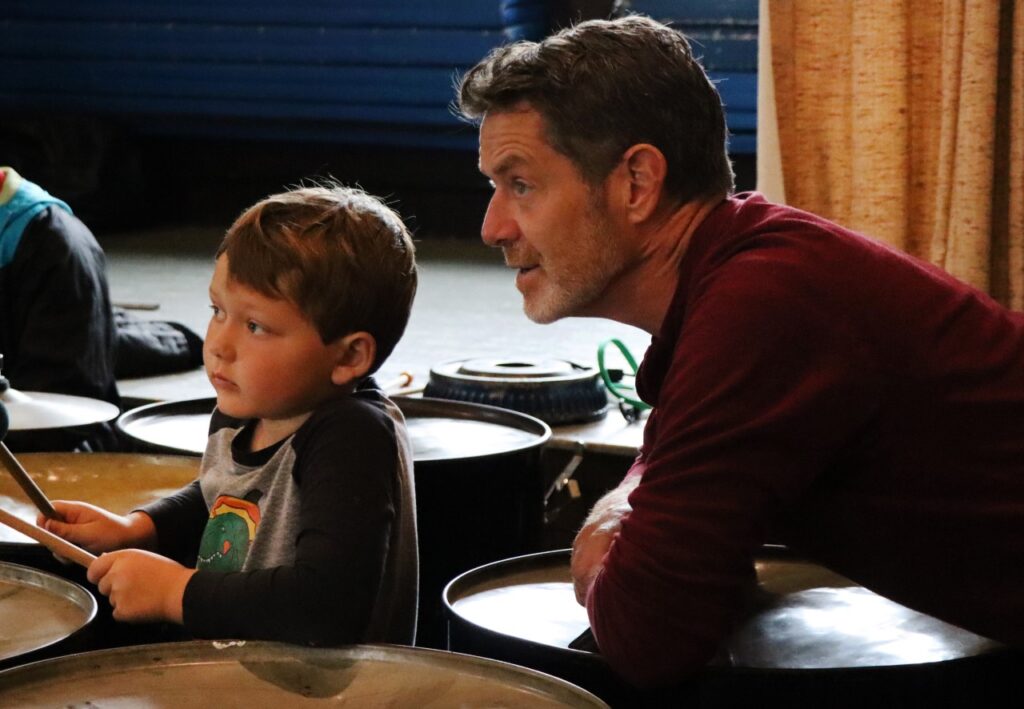 Color photo of a man and a child playing the drums