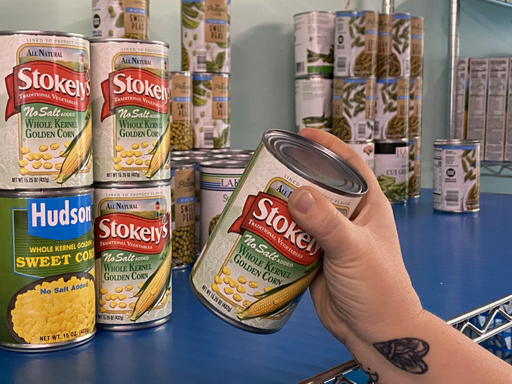 A hand grabbing a can from a shelf