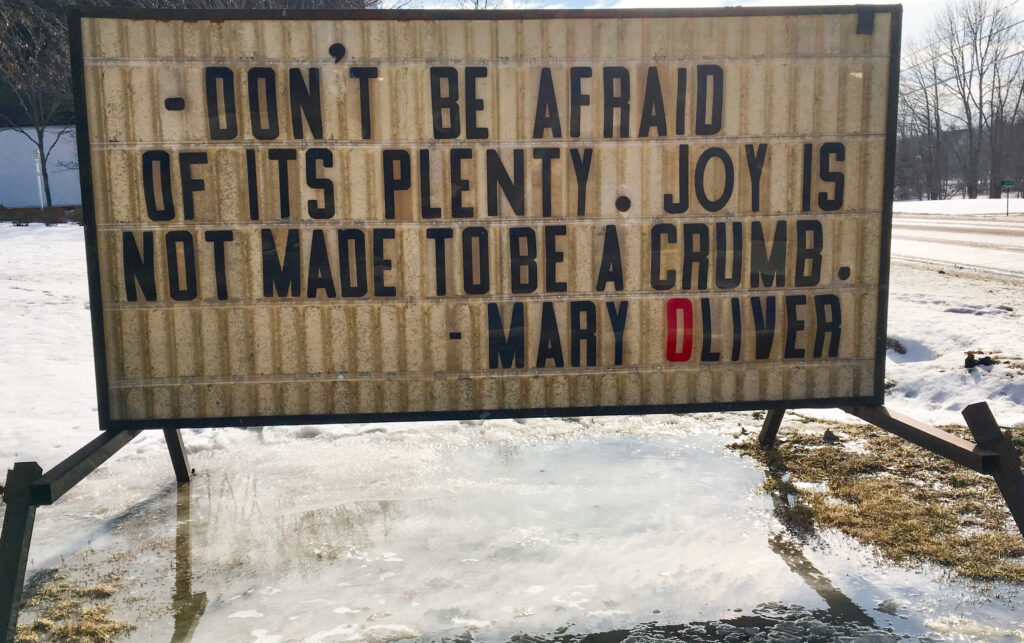Color photo of a sign that says "Don't be afraid of its plenty. Joy is not made to be a crumb. - Mary Oliver"