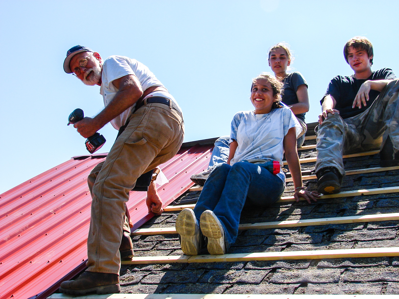 A color picture of four people working on the roof of a house