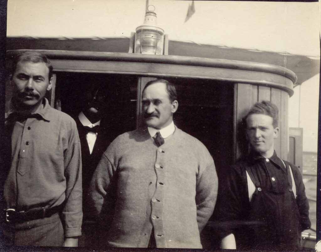 A black and white photo of four men on a boat