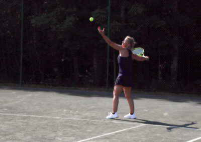 A color photo of a woman hitting a tennis ball