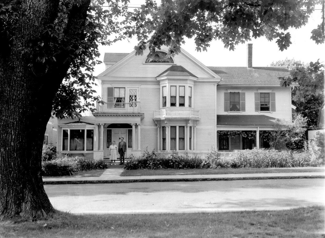 A black and white photo of a large house (Sargent House) with a man and a woman standing in front of it