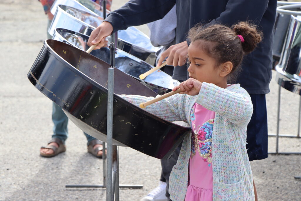 A young girl standing in front of a steel pan