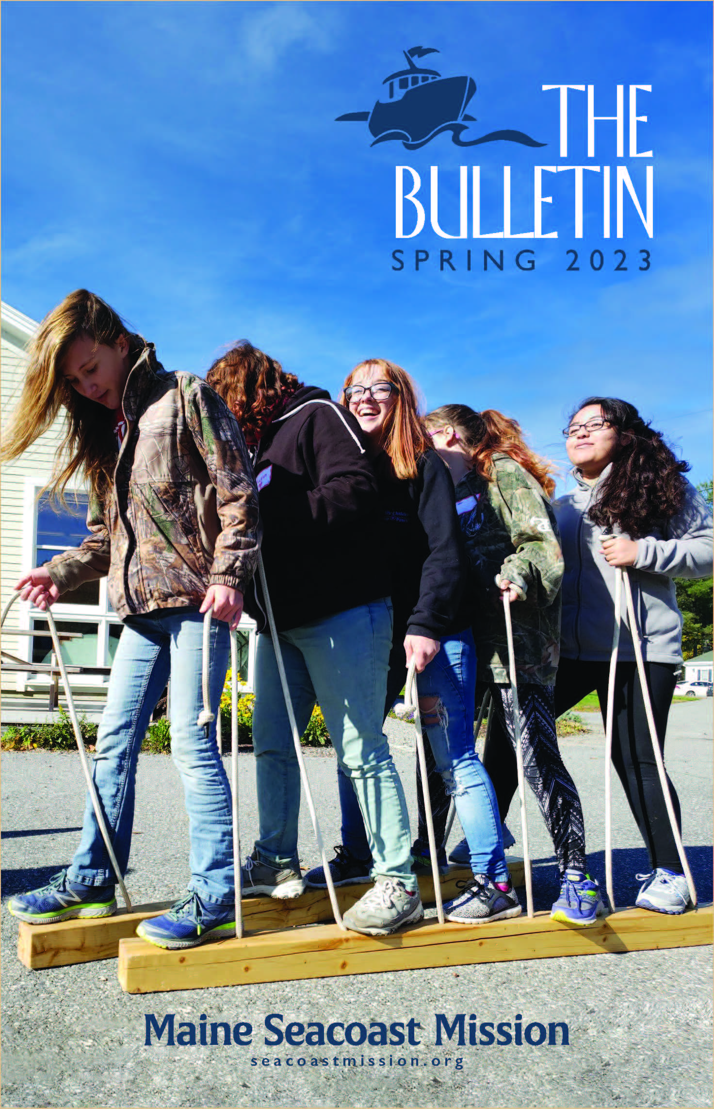 The cover of the Mission's The Bulletin with five girls on the font cover. They are standing on two pieces of wood that are being lifted by pieces of rope.