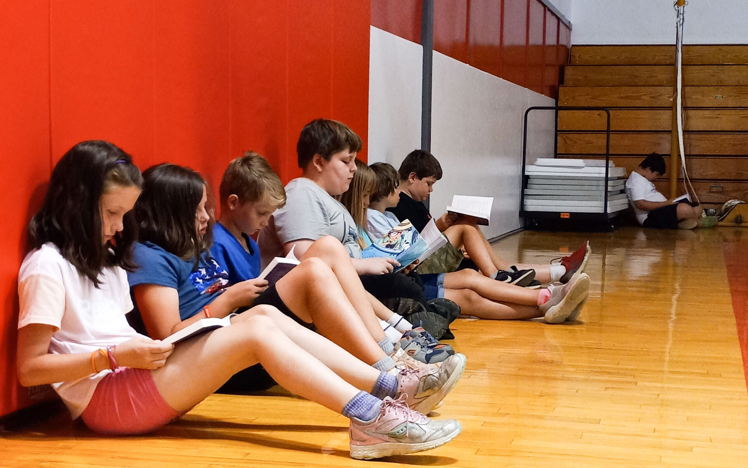A color photo of 8 students reading in a school gym