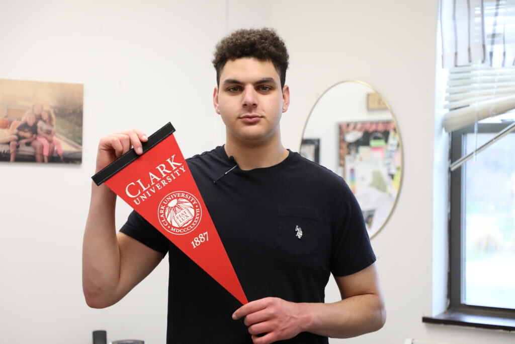Photo of a young man holding a pennant that says Clark University