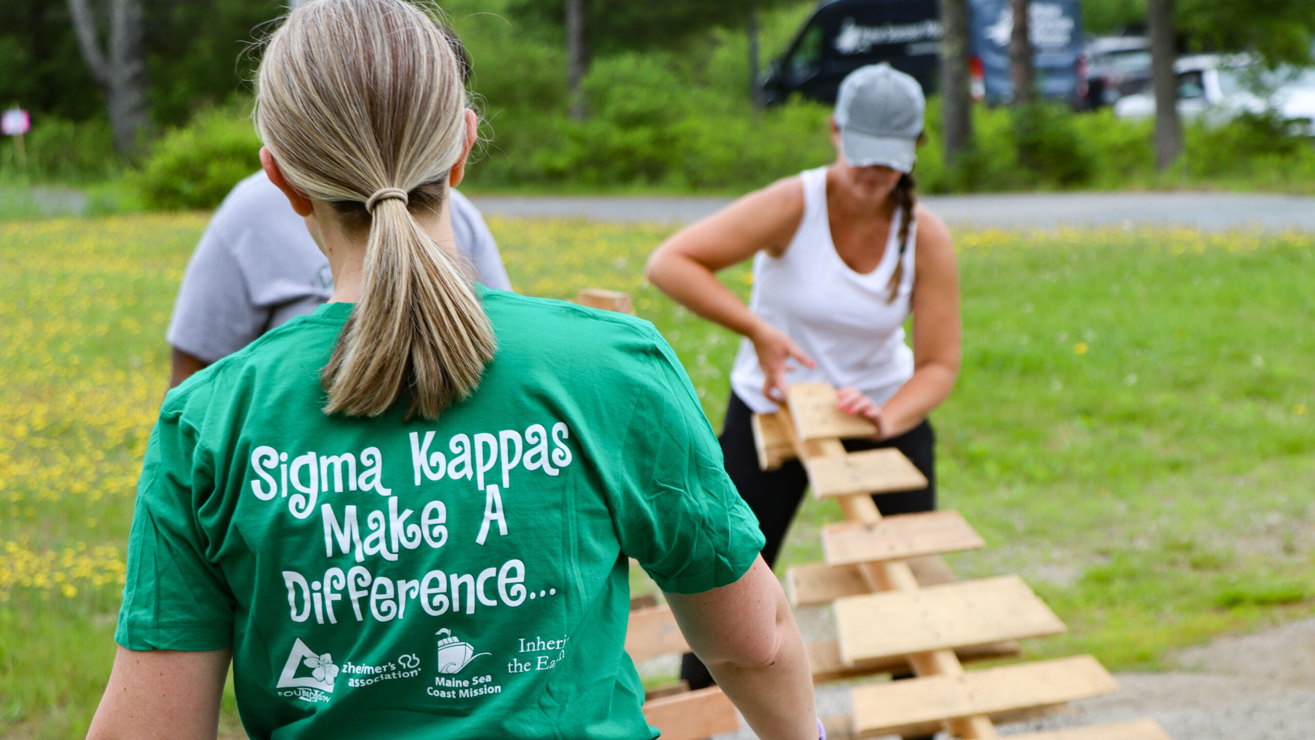 Photo of three people with one wearing a shirt that says "Sigma Kappas make a difference" with the Mission's logo