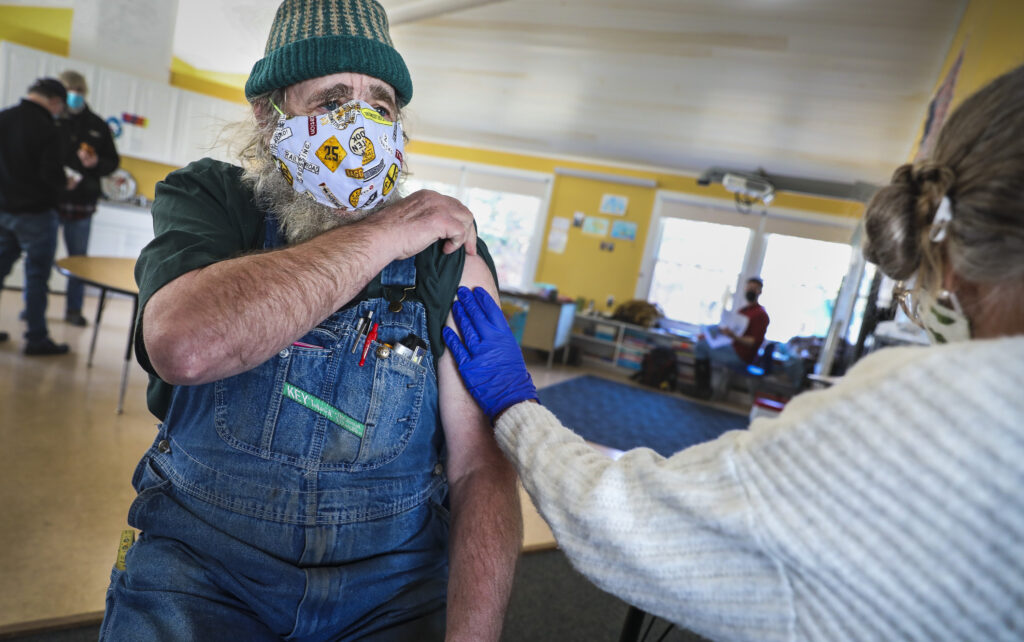 MATINICUS, ME - 3/4/2021 Paul Murray, telephone repair man and propane dealer, gets a vaccine from Peggy Atkins Erin Clark/Globe Staff