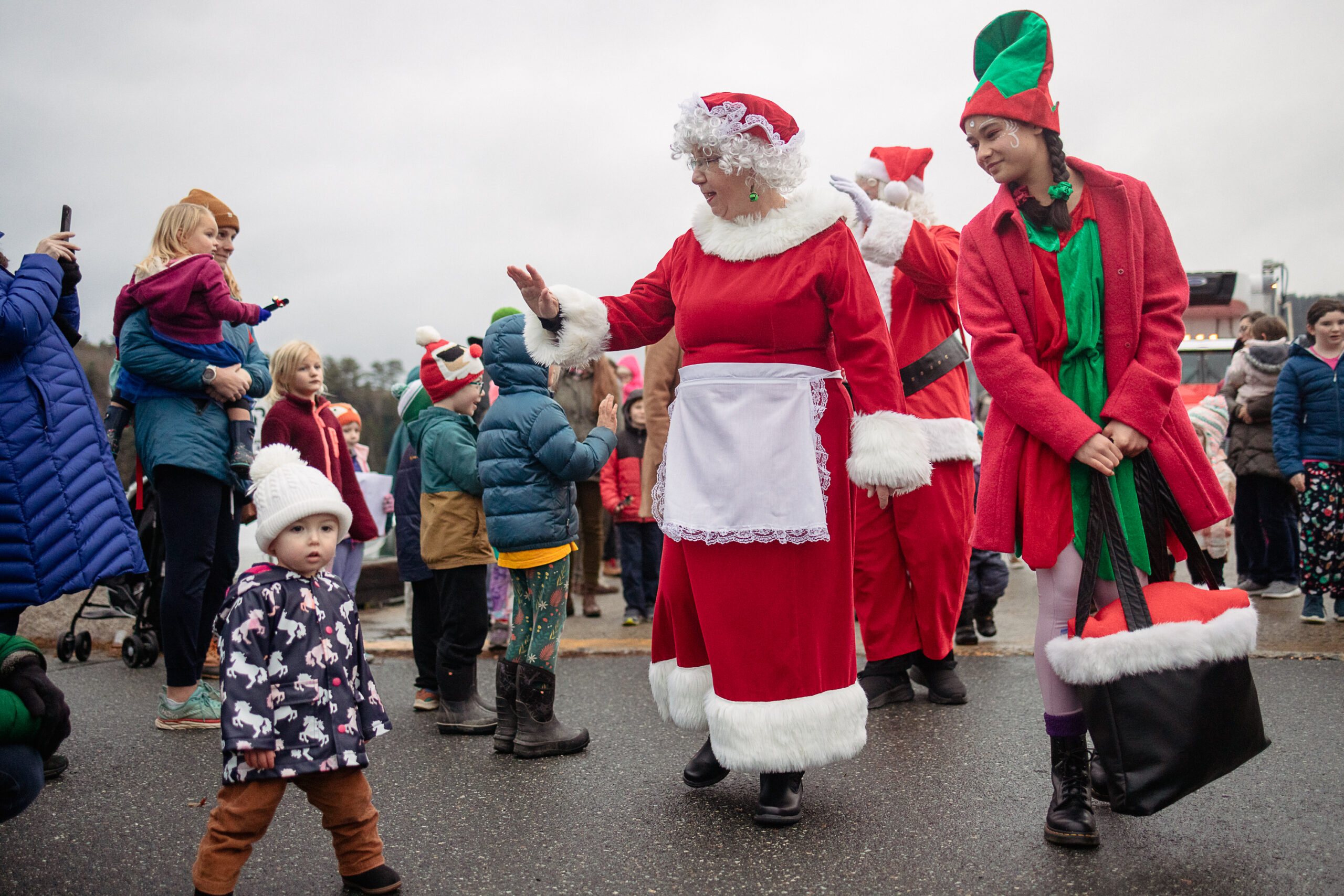 A young girl wearing a Santa hat smiles for the camera while coloring