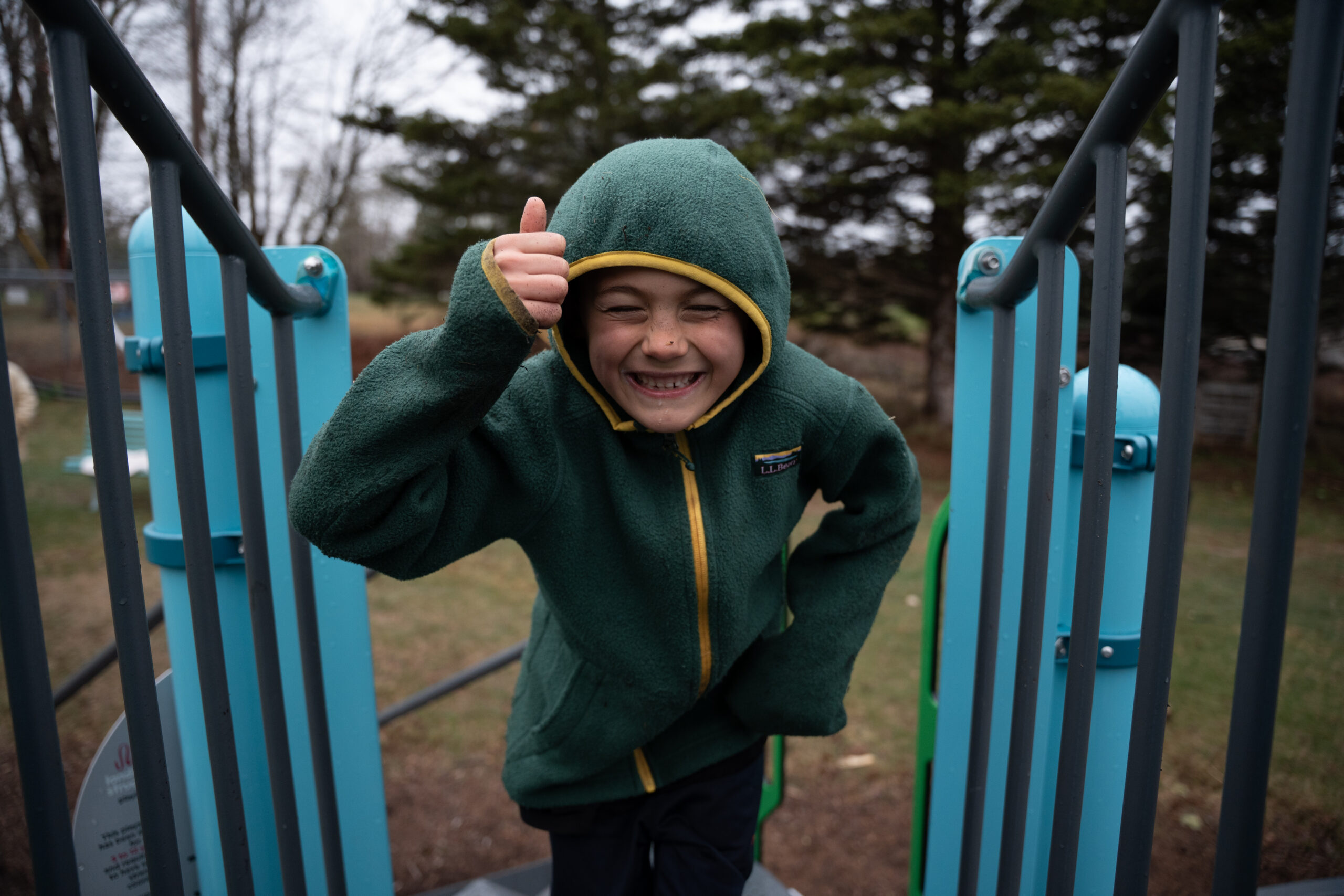 Boy on playground displaying a thumbs up 